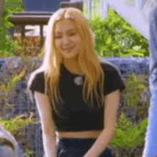 a close up of a woman wearing a black crop top and black skirt .