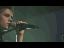 a man singing into a microphone with his hand on his chin