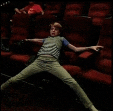 a young boy in a striped shirt is laying on the floor in a theater
