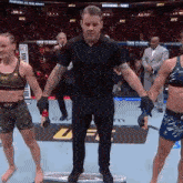 a referee is standing in front of two female fighters in a ufc fight .