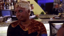a woman is sitting at a bar with a bravo logo in the background