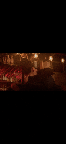 a man is standing in front of a bar full of bottles of alcohol