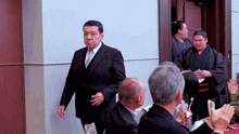 a man in a suit and tie is walking through a crowd of people