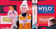 a person holding a trophy in front of advertisements for hylo