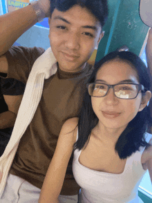 a boy and a girl are posing for a picture and the girl is wearing glasses and a white tank top