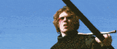 a silhouette of a man holding a sword standing next to a body of water