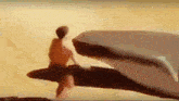 a man is sitting on a rock next to a whale in a painting .