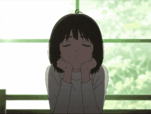 a girl with her eyes closed has her hands on her chin