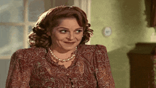a woman wearing a paisley top and a pearl necklace