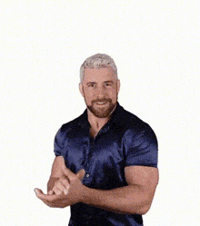 a man with a beard wearing a blue shirt is dancing and smiling .