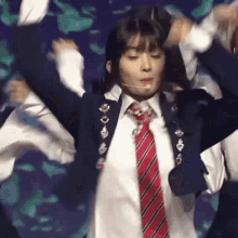 a woman in a school uniform and tie is dancing on stage .