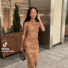 a woman in a yellow dress is holding a purse and has a tiktok account