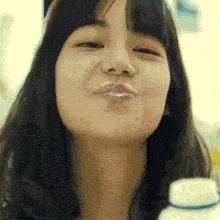 a close up of a woman making a funny face while holding a bottle .