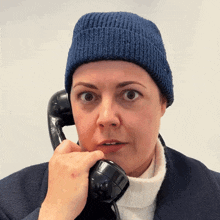 a woman in a blue hat is talking on a telephone