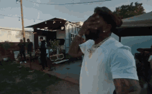 a man in a white shirt is covering his face