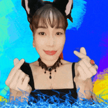 a woman wearing a cat ear headband is making a heart with her hands