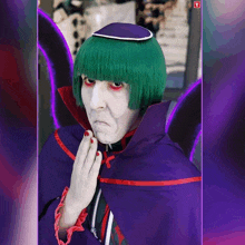a man with green hair and red eyes is wearing a purple cape and white face paint