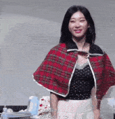 a woman wearing a plaid cape and a polka dot top is standing in front of a sign that says luckily