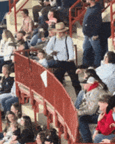 a crowd of people sitting in a stadium with a red fence