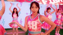 a group of cheerleaders wearing pink uniforms with the number 48 on the front