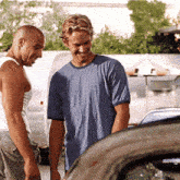 two men are standing next to each other and one has a blue shirt on