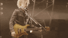 a man playing a guitar and singing into a microphone