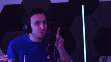 a man wearing headphones is pointing at something in front of a microphone
