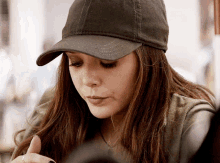 a woman wearing a baseball cap is looking down at something