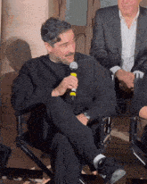 a man in a black sweater is holding a microphone