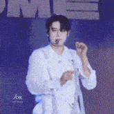 a man in a white shirt is standing on a stage with a microphone .