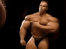 a very muscular man in a bikini is standing in a dark room .
