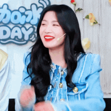 a woman wearing a blue jacket is smiling in front of a sign that says ' day '