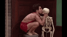 a man is kissing a skeleton on the cheek .