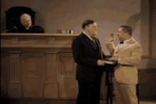 a man in a yellow suit is being sworn in by another man in a black suit
