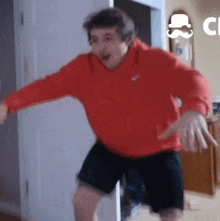 a man in a red nike hoodie and black shorts is dancing