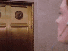 a woman standing in front of a gold door with a green circle in the middle