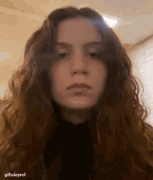 a young woman with curly hair is looking at the camera .