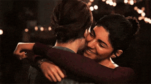 two women are hugging each other in a dark room and one of them is crying .