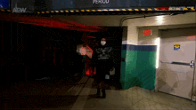 a person wearing a mask walks through a tunnel with a sign that says exit on it