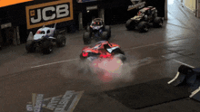three monster trucks are racing on a track with a jcb sign in the background