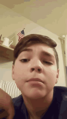 a young boy looks at the camera with an american flag in the background