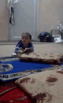 a little boy is reading a book while laying on the floor