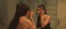 a woman applying makeup in front of a mirror with a cross on her neck