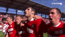 a group of soccer players are celebrating a goal with fc bayern on the bottom