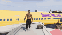 a shirtless man stands in front of a yellow airplane that says adios airlines