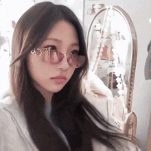 a girl wearing a pair of pink sunglasses looks at her reflection