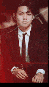 a man in a suit and tie is sitting in a dark room