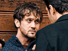 a man with a beard is looking at another man 's face