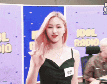 a woman in a black dress is standing in front of a sign that says " idol radio "