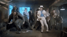 a man in a white hat is dancing with a group of people